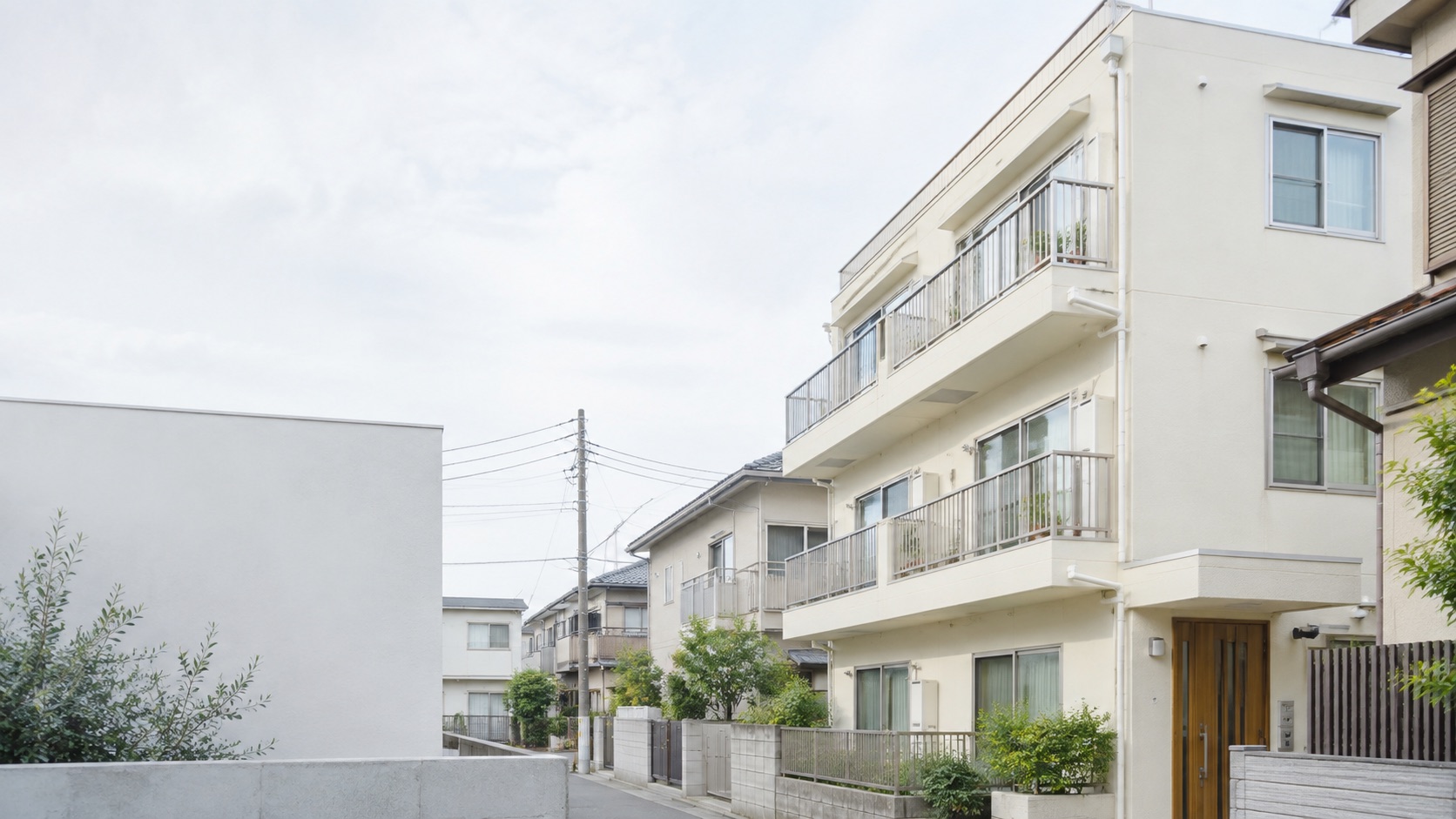 日中の住宅街に立つ、手入れされた集合住宅のイメージ
